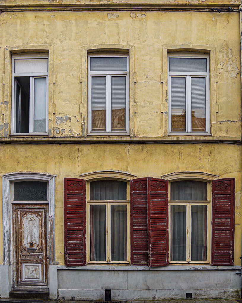 Yellow house façade with red shutters in the Trichon district of Roubaix.