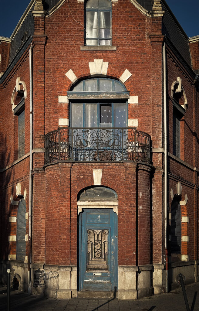 Red brick house with blue woodwork. Architecture from the 1930s, or perhaps even earlier.